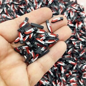 May include: A large pile of black and red plastic knife charms. The knives have a white blade and a red handle.