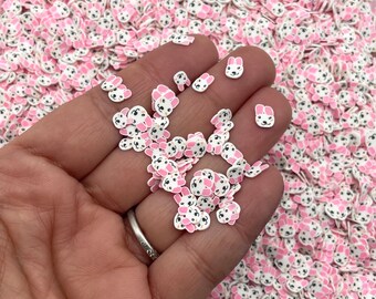 Pode incluir: Um close-up de uma mão segurando um monte de confeitos de rosto de coelho branco e rosa. Os confeitos são pequenos e têm olhos pretos e orelhas cor-de-rosa.