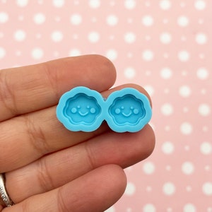 May include: A blue silicone mould with two cloud shapes, each with a smiling face.