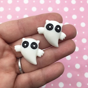 Pode incluir: Dois encantos em forma de fantasma brancos com olhos pretos. Os encantos são feitos de plástico e têm um acabamento brilhante.