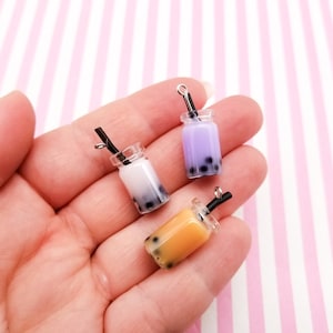 Pu&ograve; includere: Tre ciondoli di bubble tea in miniatura con bevande di diversi colori: viola, bianco e arancione. Ogni ciondolo ha una cannuccia nera e un anello d'argento per appenderlo.