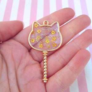 May include: Gold-tone key charm with a clear cat-shaped resin top filled with gold glitter and yellow stars.