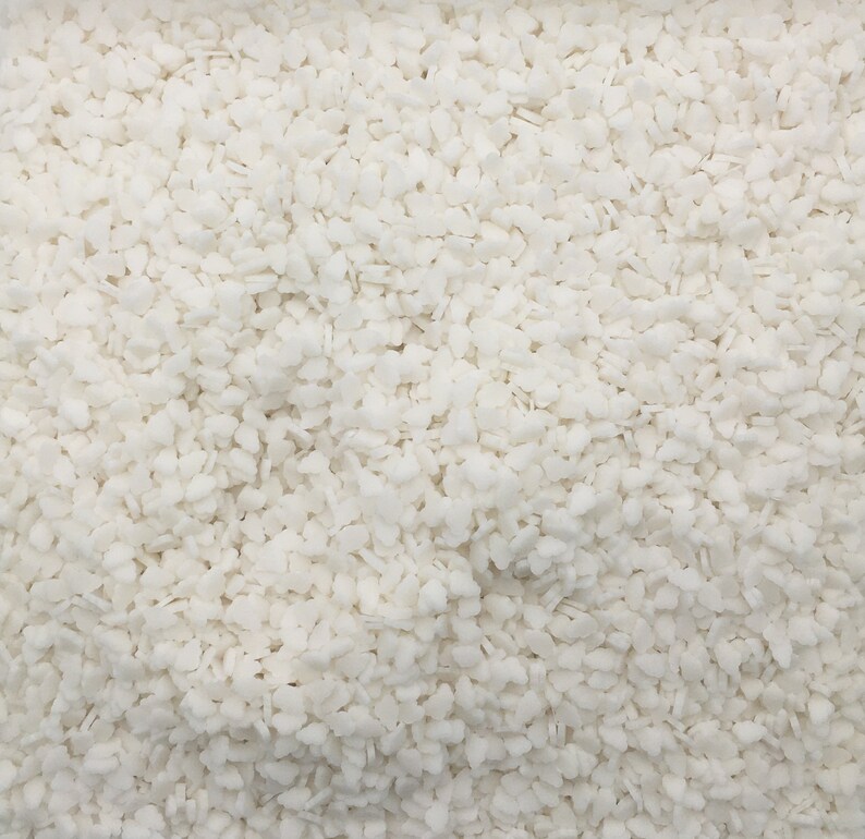 May include: Close-up of a white, granular substance. The image is filled with small, irregularly shaped pieces, creating a textured, almost crystalline appearance. The overall effect is a uniform, bright white surface.
