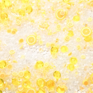 May include: An overhead view of a display of lemon slices and ice cubes. The yellow lemon slices are interspersed with clear ice, creating a bright and cool visual. The image suggests refreshment and a summery feel.