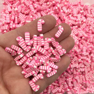 May include: A large quantity of pink and white candy cane shaped polymer clay charms. The charms are small and perfect for adding a festive touch to crafts.