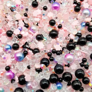 Può includere: Un mix di zuccherini rosa, neri e trasparenti, perline e altri elementi decorativi. Gli zuccherini hanno la forma di fiori e quadrati.