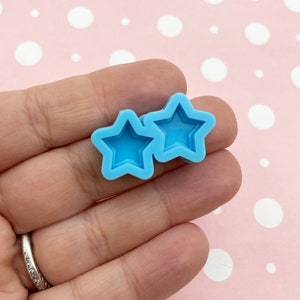 May include: Two light blue silicone molds shaped like stars. The molds are designed to create star-shaped resin pieces.
