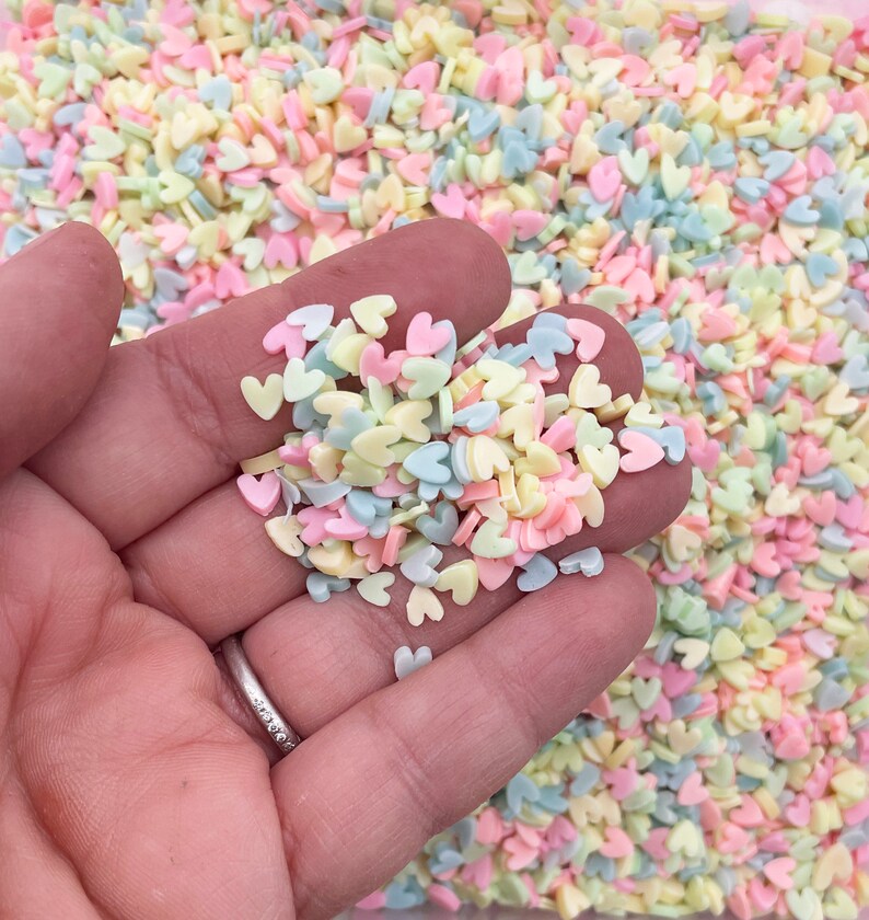 May include: A handful of pastel pink, yellow, and blue heart-shaped sprinkles.