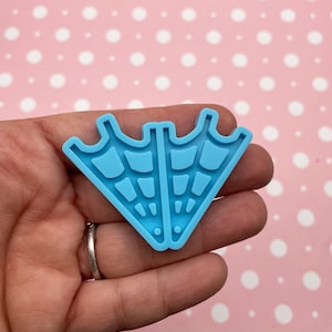 May include: A light blue silicone mold shaped like two triangular spiderwebs. The mold is designed for making resin crafts.