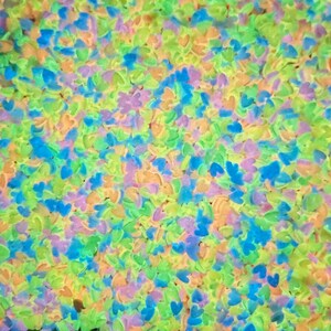 May include: A close-up image of a large quantity of small, heart-shaped sprinkles in a variety of pastel colors, including blue, green, yellow, and purple.