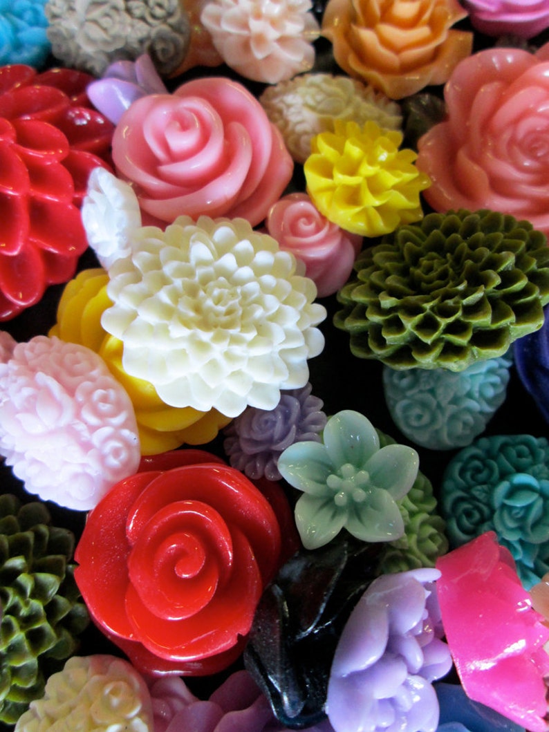 May include: Assortment of colorful, decorative, and unique flower-shaped buttons. The buttons are made of various materials, including plastic, metal, and fabric. The buttons are in a variety of colors, including red, pink, white, green, yellow, and blue.