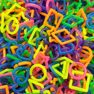 The image is a colorful pile of various plastic shapes, including letters, numbers, and geometric forms, creating a vibrant and playful visual.