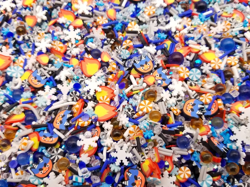 Peut inclure: Un m&eacute;lange color&eacute; de vermicelles, comprenant du bleu, de l'orange, du blanc et du noir. Les vermicelles sont en forme de flocons de neige, de cannes en sucre, de flammes et de visages de dessins anim&eacute;s.
