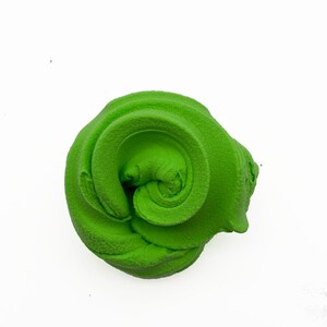 May include: A bright green, textured, swirl-shaped object, possibly a decorative item or a component of a larger design. The object is set against a plain white background, highlighting its form and color.