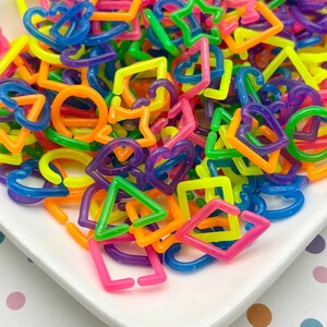 A white plate filled with a colorful assortment of plastic shapes, including various geometric and heart-shaped designs, creating a vibrant and playful visual display.