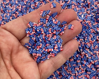 Op de afbeelding: Een handvol kleine, rood-wit-blauwe, stervormige sprinkles. De sprinkles hebben de vorm van de Amerikaanse vlag.