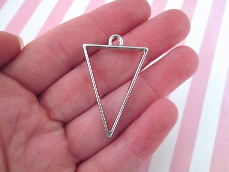 May include: Silver triangle pendant frame with a loop at the top for hanging.