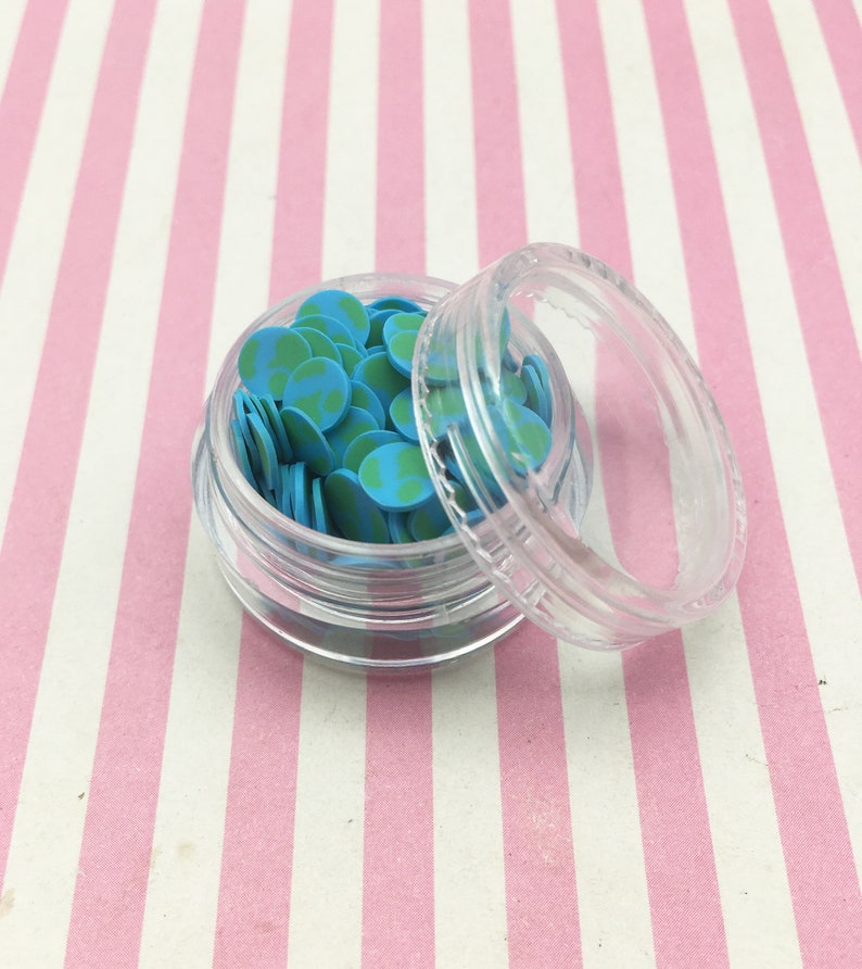 May include: A clear plastic container filled with small blue and green earth-shaped sprinkles. The container has a clear lid.