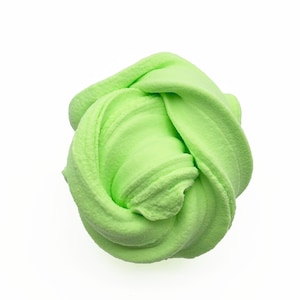May include: A vibrant, lime green slime toy, presented against a clean white backdrop. The soft, textured material is molded into a swirling, rounded shape, showcasing its pliable nature. This sensory toy is ideal for children and adults.