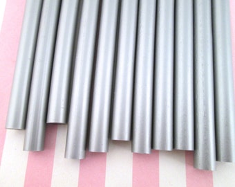 May include: A set of ten silver-colored wax sticks for sealing envelopes or letters. The sticks are arranged in a row, with the ends of the sticks facing the viewer.