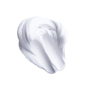 May include: A close-up of a white, creamy substance, possibly a cosmetic product, against a stark white background. The texture appears smooth and thick, with visible brushstrokes creating a swirling pattern.