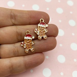May include: Two gold-coloured gingerbread man charms with white icing and red candy canes. The gingerbread men are wearing red and white Santa hats.