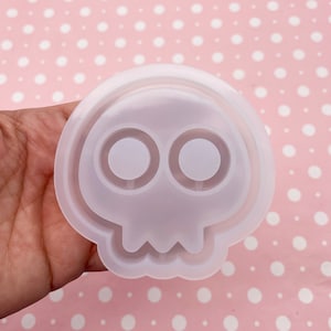 May include: White silicone mold shaped like a skull with two round eye sockets.