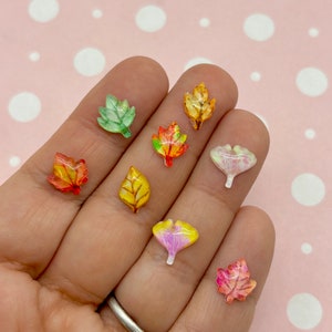 May include: Assortment of eight resin fall leaves in various colors and designs, including yellow, orange, red, green, and pink. The leaves are small and perfect for crafting projects.