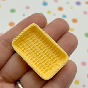 May include: A small, yellow, rectangular tray with a woven pattern. The tray is made of resin and is perfect for miniature crafts.