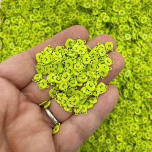 May include: A handful of lime green bear face shaped resin sprinkles with black eyes and pink cheeks.