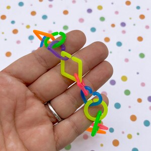 A hand holding a colorful plastic bracelet against a background of multicolored polka dots.