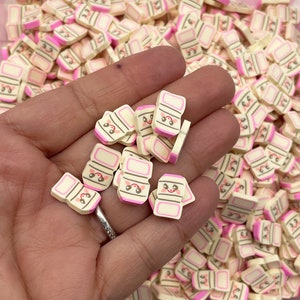 May include: A large pile of small, white and pink milk carton shaped charms with a cute cartoon face.
