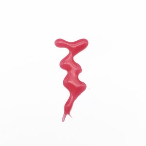 May include: A pink, gooey substance drips down a white surface, forming a unique shape.
