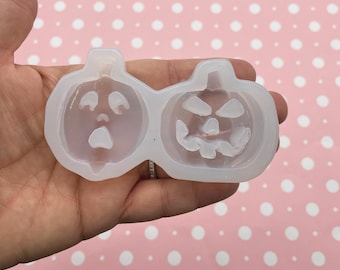 May include: A clear silicone mold with two pumpkin shapes. One pumpkin has a traditional jack-o'-lantern face, while the other has a more cartoonish, surprised expression.