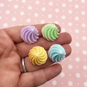 Peut inclure: Quatre décorations de bonbons en forme de spirale de couleur pastel. Les couleurs sont le violet, le vert, le jaune et le bleu.