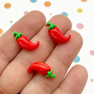 May include: Three red chili pepper shaped polymer clay charms with green tops.