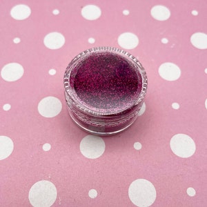 May include: A small clear jar filled with pink glitter.