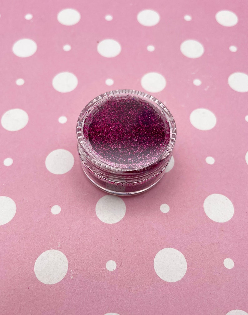 May include: A small clear jar filled with pink glitter.