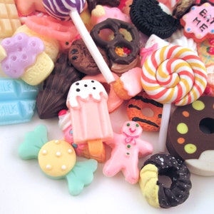 May include: Assortment of colorful miniature candy and food charms, including a donut, lollipop, cupcake, gingerbread man, and chocolate bar. The charms are made of plastic and have a realistic appearance.