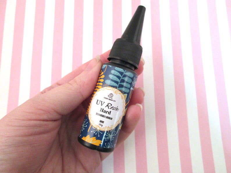 May include: A small bottle of UV resin with a black cap and a floral design label. The label reads "UV Resin Hard" and "25g".