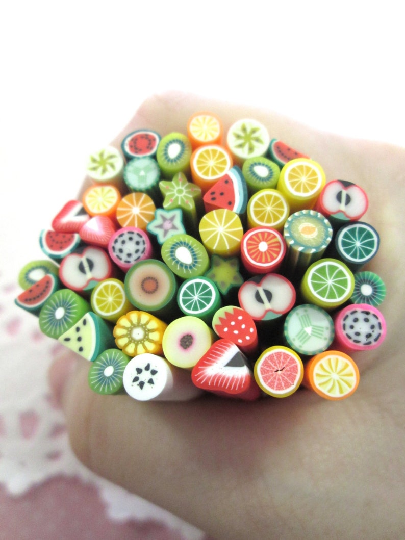 May include: A collection of colorful polymer clay fruit slices, including watermelon, kiwi, lemon, lime, strawberry, and orange, arranged in a circle.