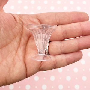 May include: A clear plastic miniature ice cream sundae dish with a fluted design and a pedestal base.