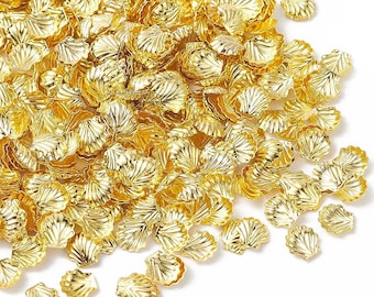 May include: A large pile of gold-colored metal seashells. The shells are scattered on a white background.
