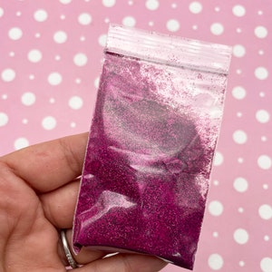May include: A small clear plastic bag filled with fine pink glitter.