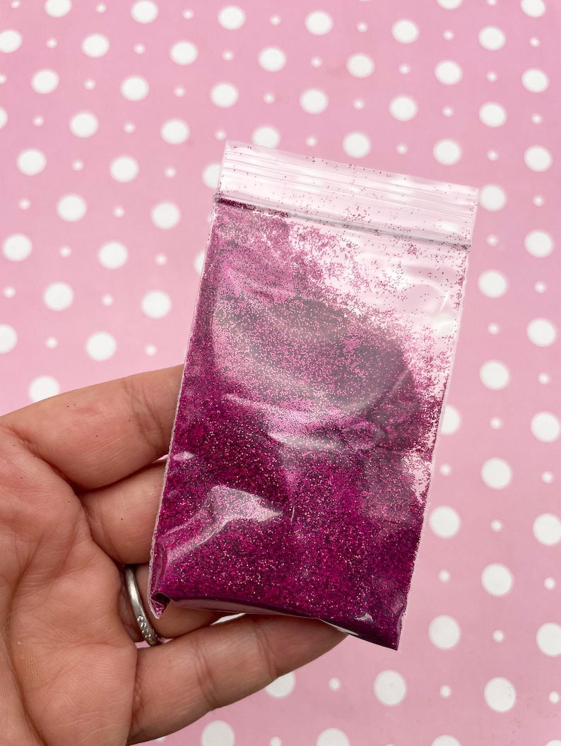 May include: A small clear plastic bag filled with fine pink glitter.