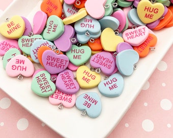 May include: A collection of colorful heart-shaped candy charms with various messages, including "Sweet Heart", "Hug Me", and "Be Mine".