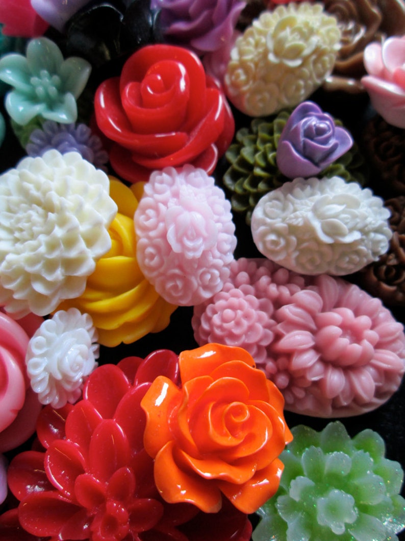 May include: Assortment of colorful resin cabochons in various flower and rose shapes. The cabochons are in shades of red, pink, orange, yellow, white, green, and purple.