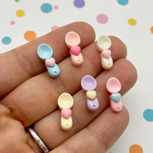 Könnte beinhalten: Sechs Mini-Plastiklöffel mit herzförmigen Akzenten in Pastellfarben: hellblau, rosa, gelb, lila und weiß.