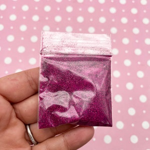 May include: A small clear plastic bag filled with fine pink glitter.
