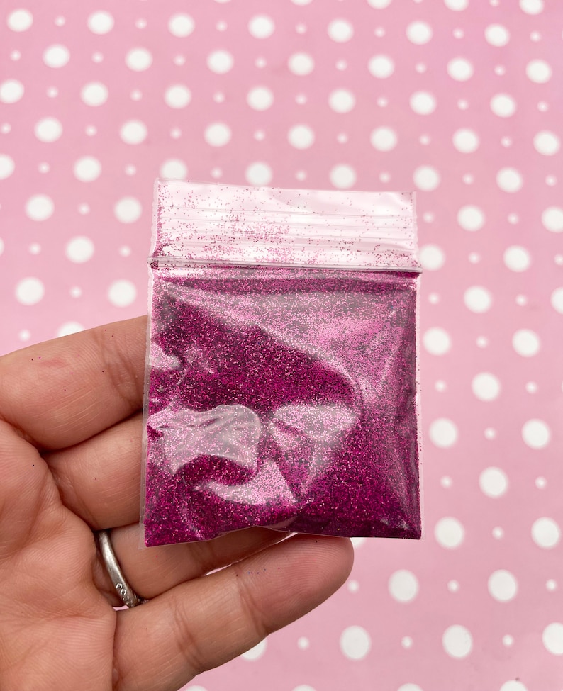 May include: A small clear plastic bag filled with fine pink glitter.